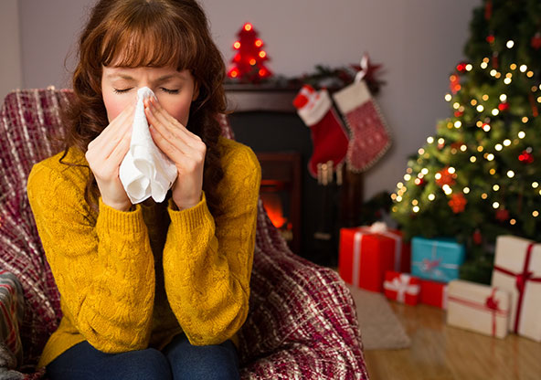 Middle aged woman who is blowing her nose and sick at Christmas time